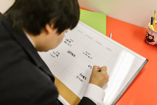 Businessperson writes in a planner on a desk, organizing weekly schedule professionally.