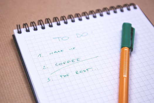 Handwritten to-do list on graph paper notebook with pen. Ideal for organizing tasks.